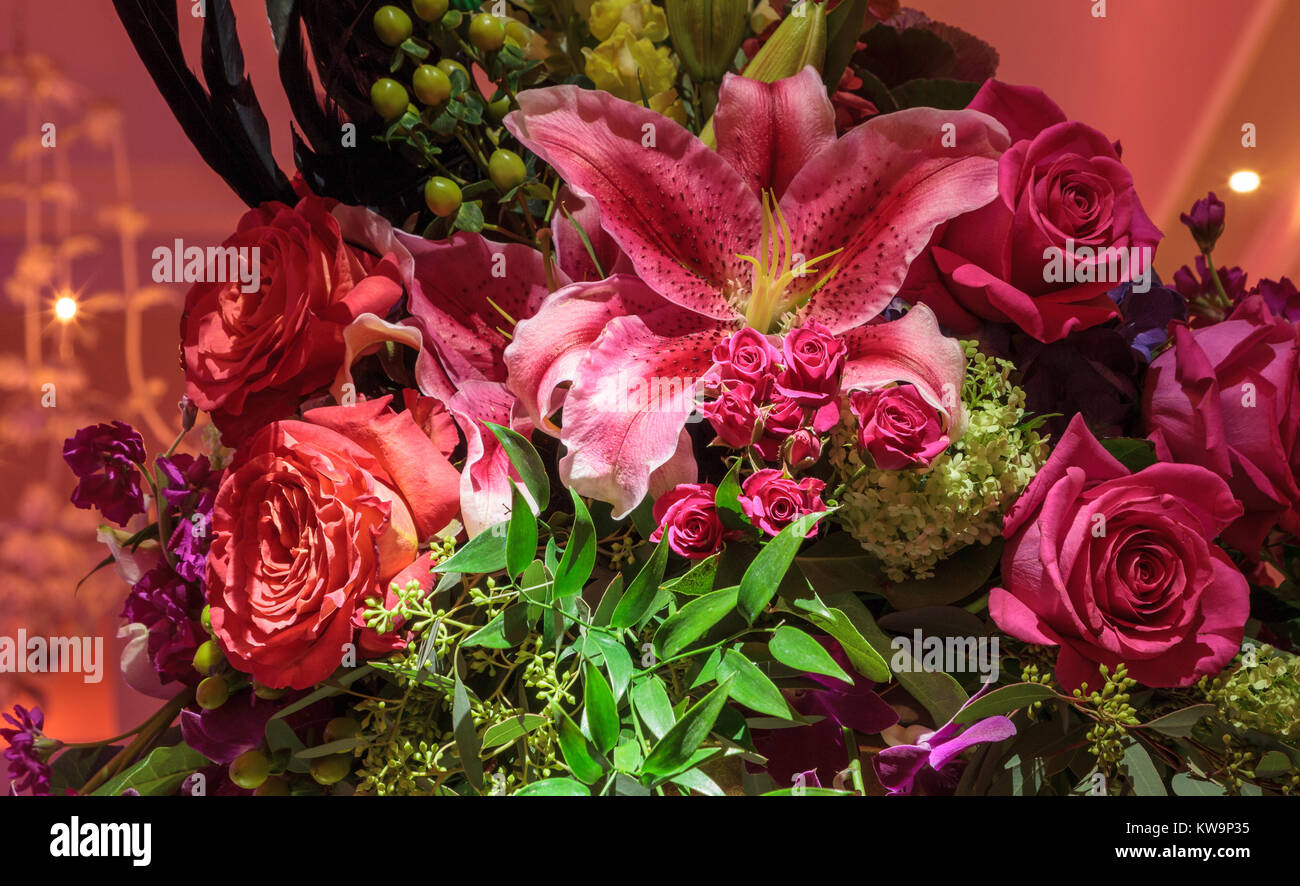 Fresh bouquet of roses, rubrum lily, hydrangea, and assorted blooms with a party mask. Stock Photo