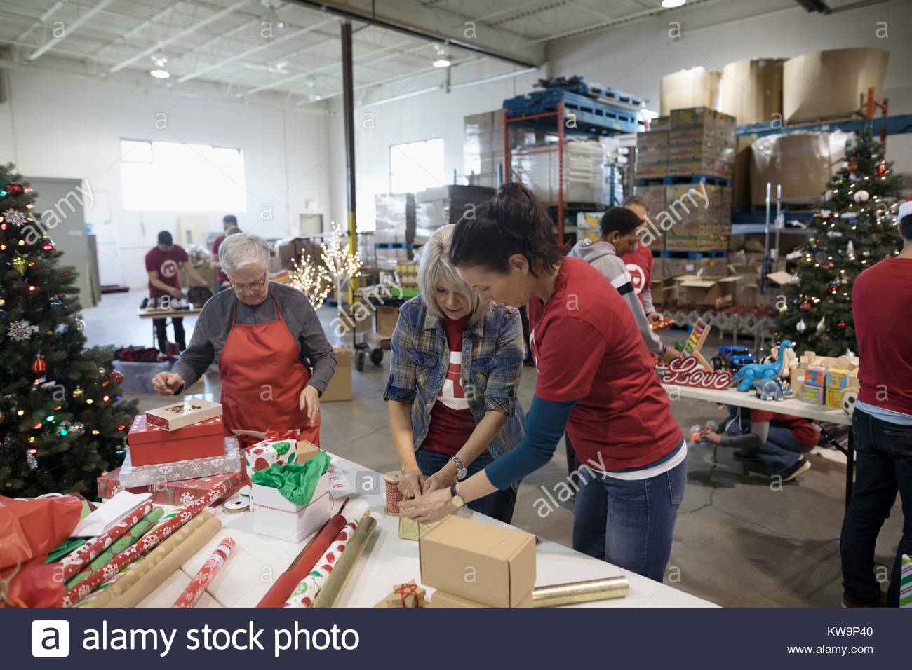 Volunteers wrapping Christmas gifts in warehouse Stock Photo Alamy