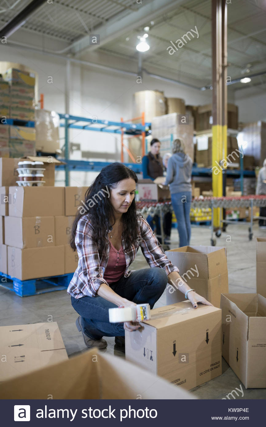 Female volunteer taping donation boxes in warehouse Stock Photo