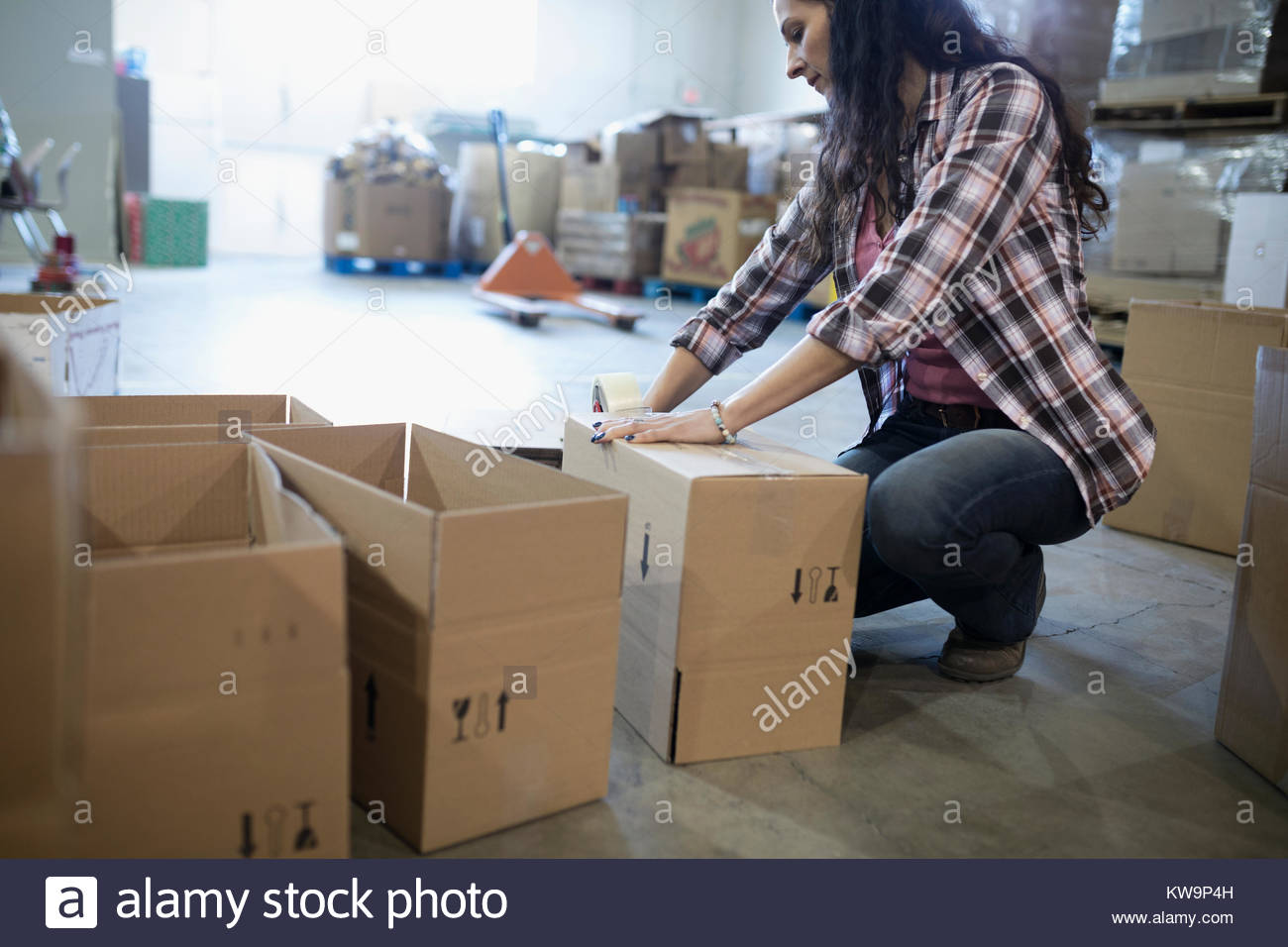 Female volunteer taping donation boxes in warehouse Stock Photo
