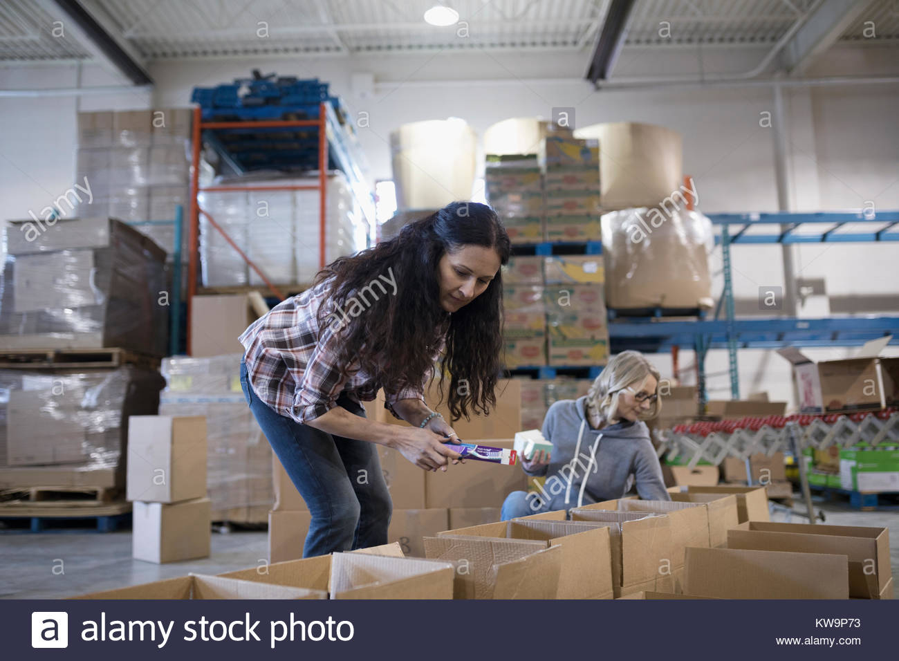 Female volunteers filling donation boxes in warehouse Stock Photo
