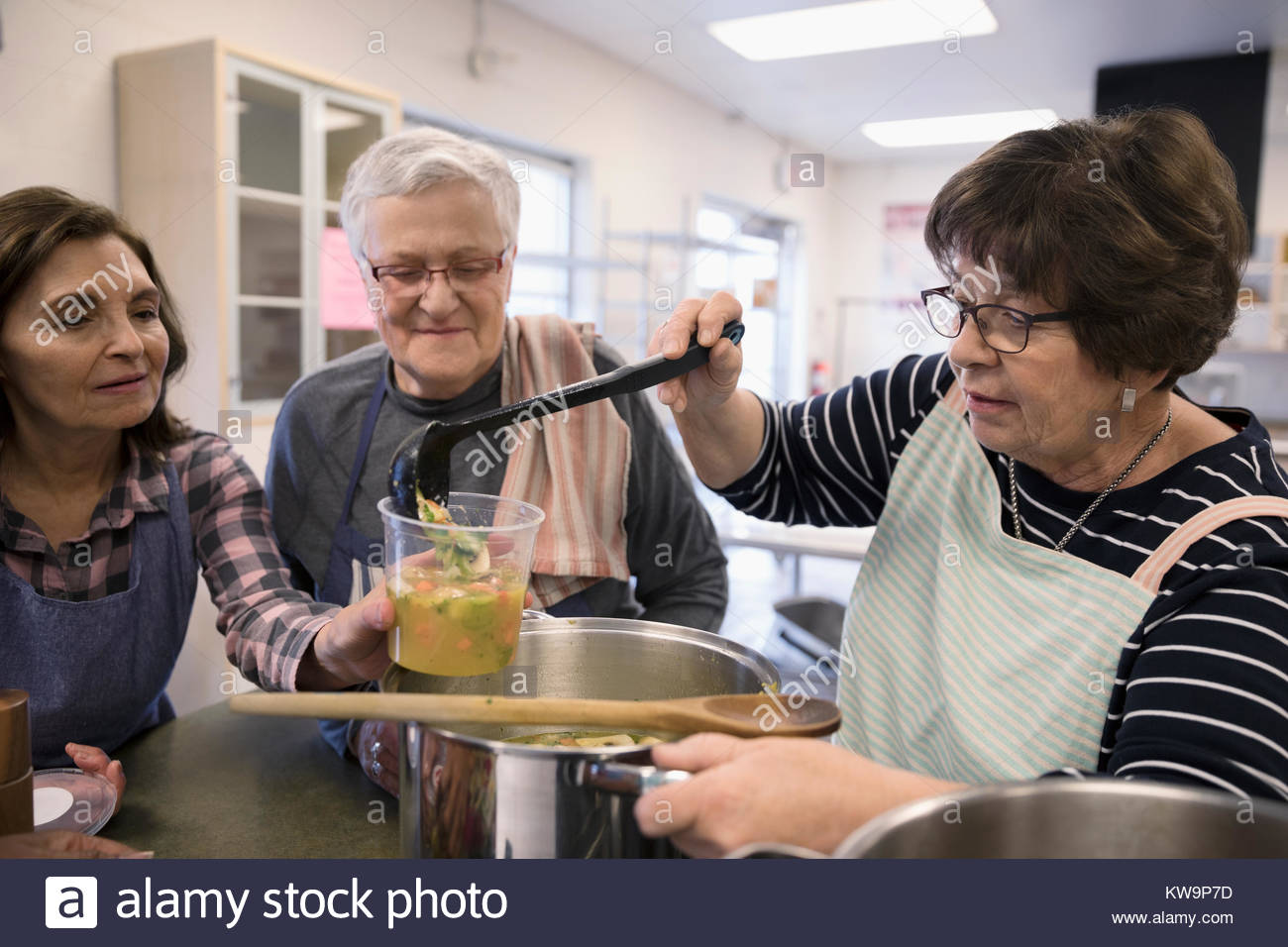 Female volunteers cooking,pouring soup in soup kitchen Stock Photo Alamy