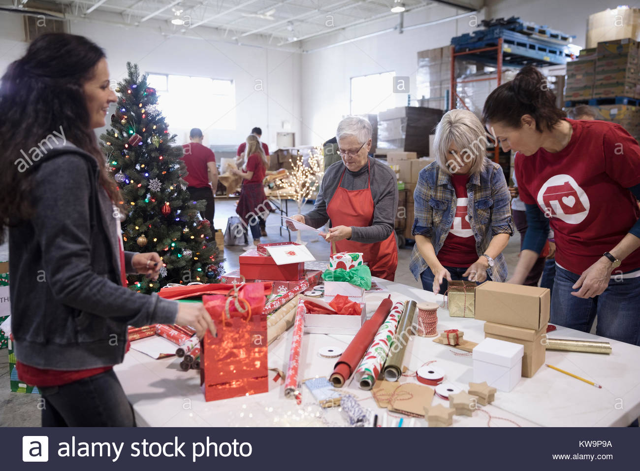 Volunteers wrapping gifts in warehouse Stock Photo Alamy
