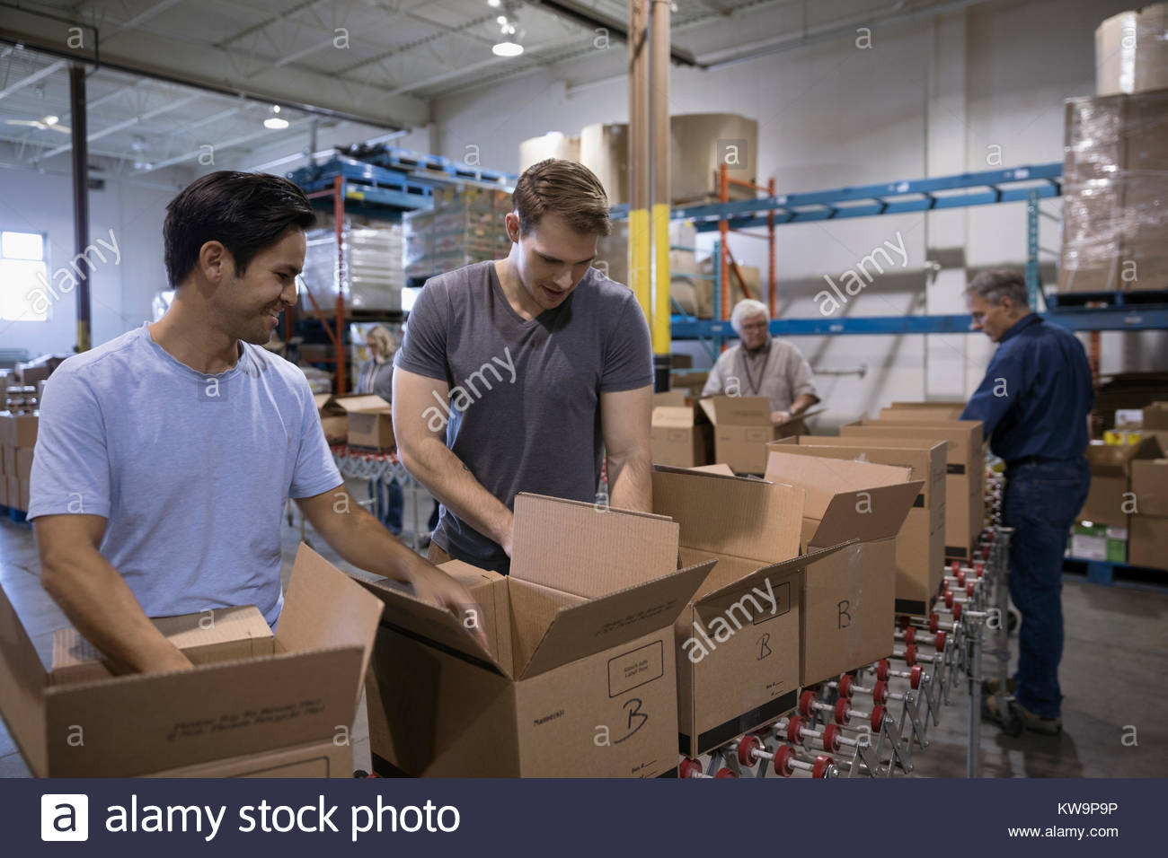 Male volunteers filling boxes for food drive in warehouse Stock Photo
