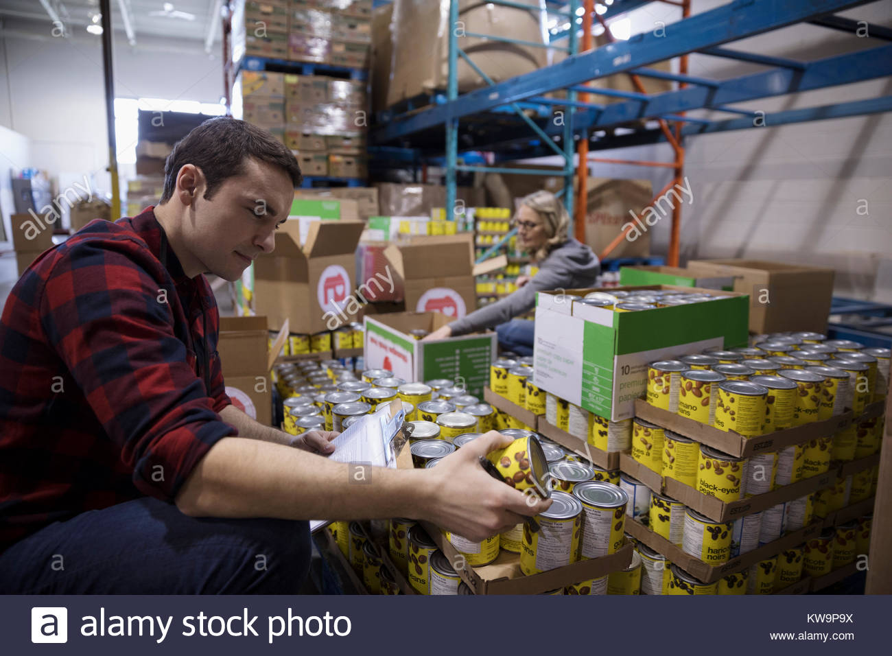 Male volunteer taking canned food drive inventory in warehouse Stock