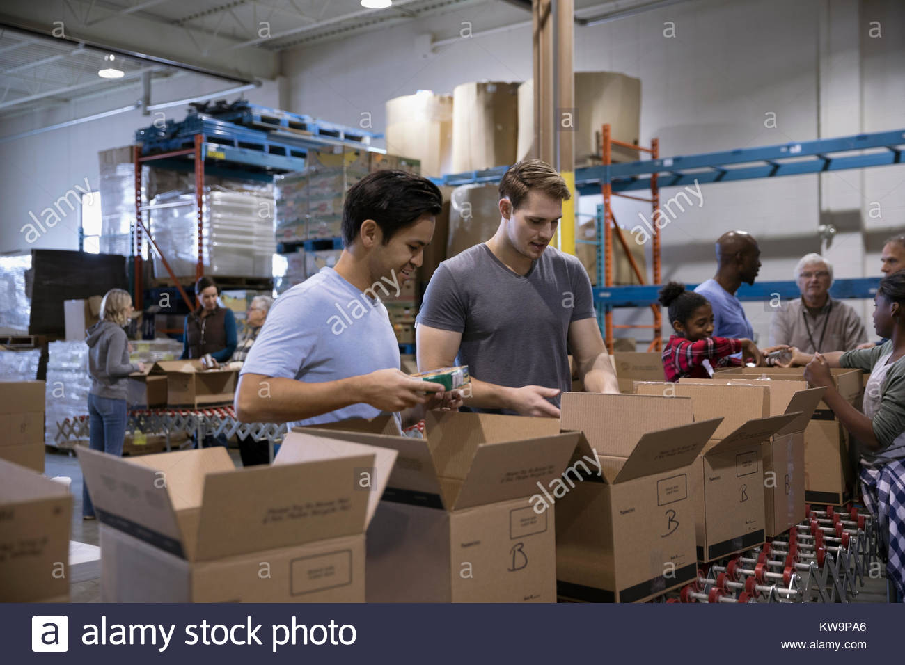Male volunteers filling boxes for food drive in warehouse Stock Photo