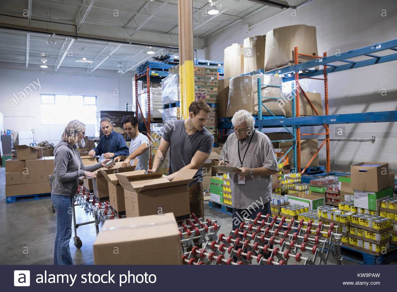 Volunteers boxing canned food for food drive in warehouse Stock Photo
