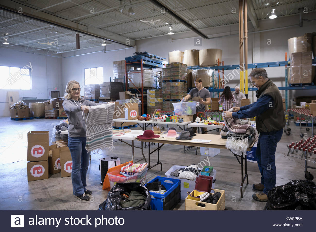 Volunteers sorting clothing and toys in warehouse Stock Photo Alamy