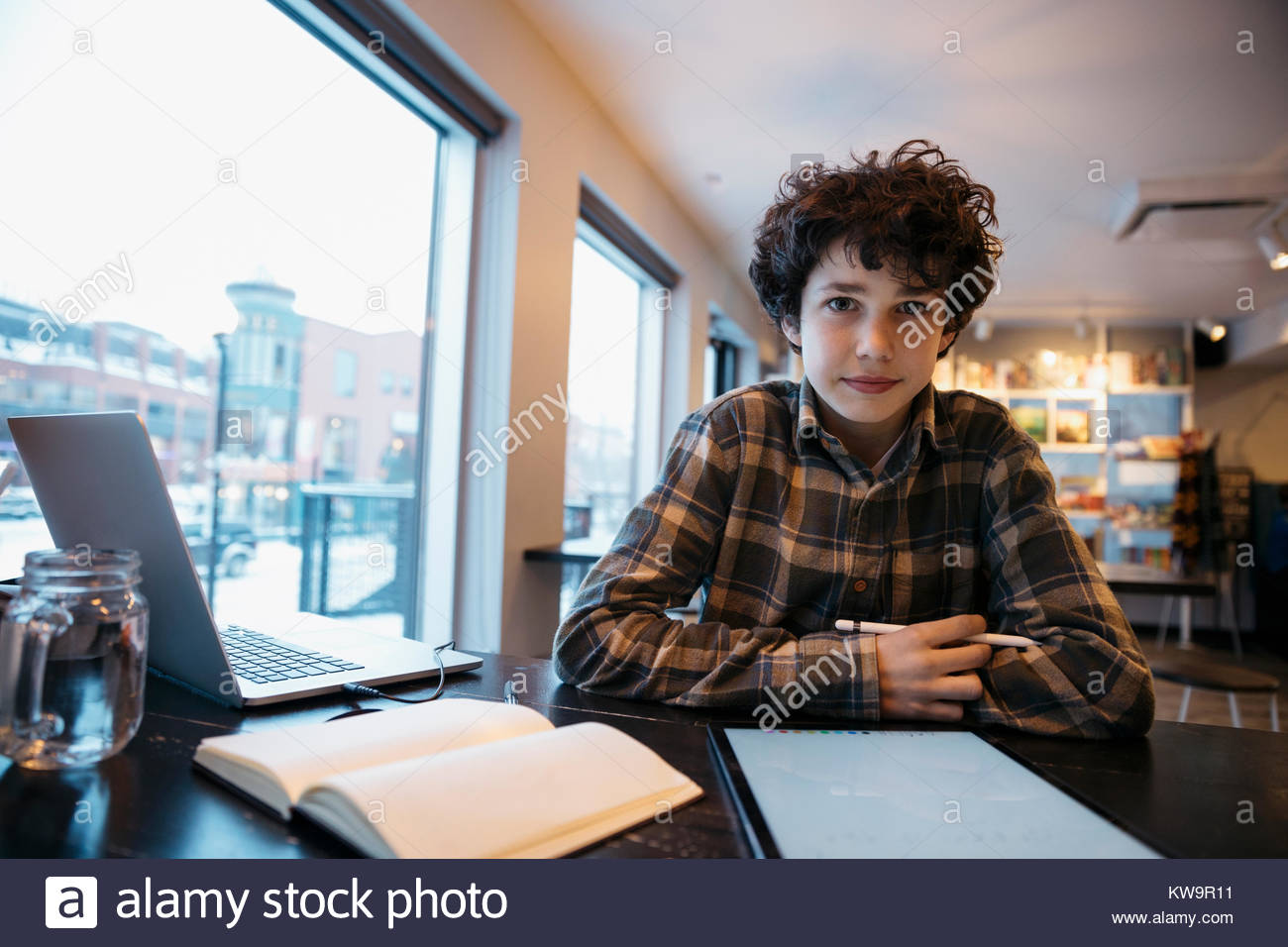 Portrait confident high school boy student studying,using stylus with digital tablet in cafe Stock Photo