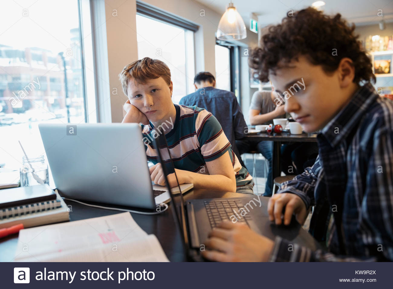 Portrait serious high school boy students studying at laptop in cafe Stock Photo