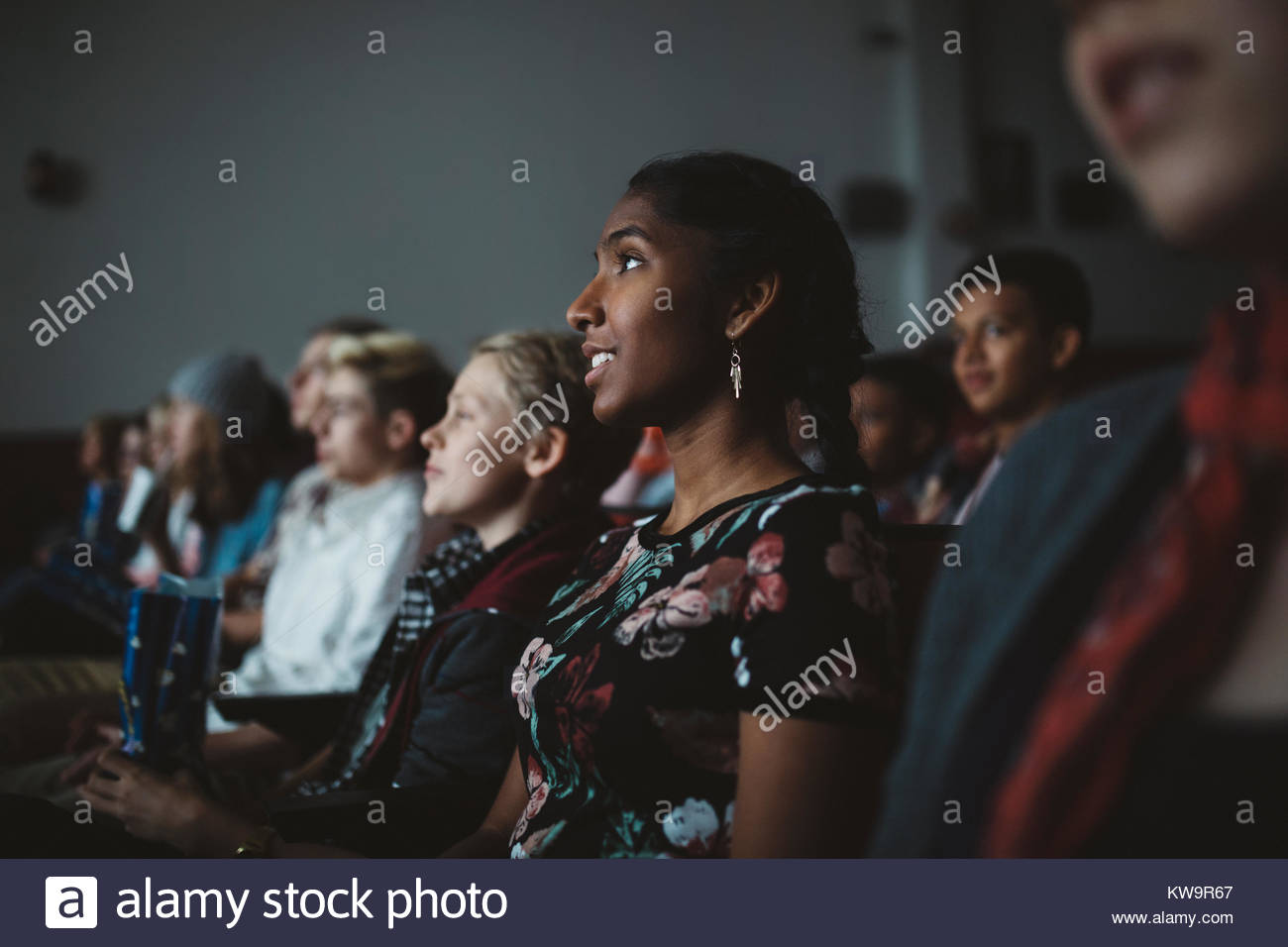 Indian tween girl watching movie in dark movie theater Stock Photo