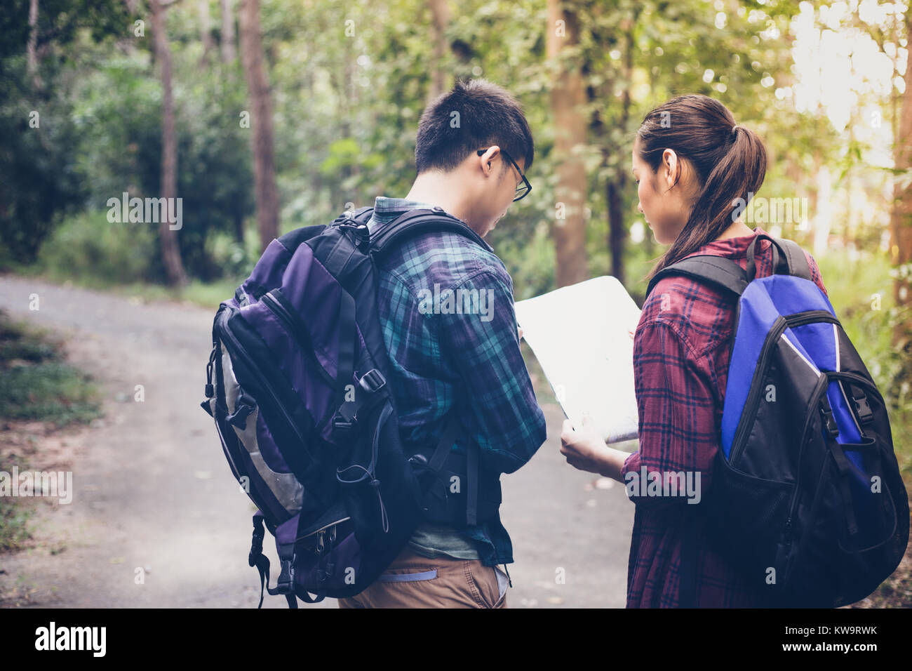 Asian Group of young people Hiking with friends backpacks walking together and looking map and taking photo camera by the road and looking happy ,Rela Stock Photo