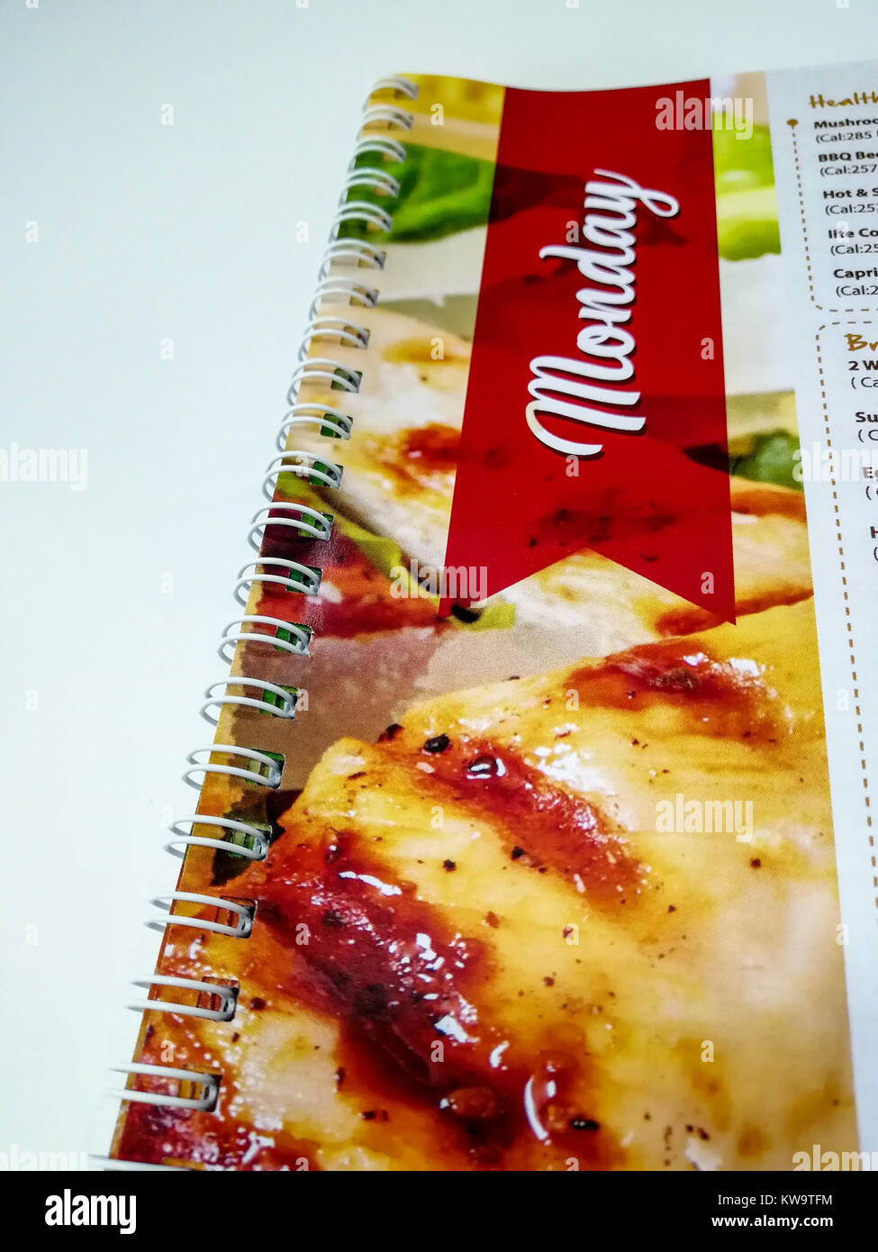 Spiral book binding with red color and chicken pictures having Monday written having white background white spiral binding Stock Photo