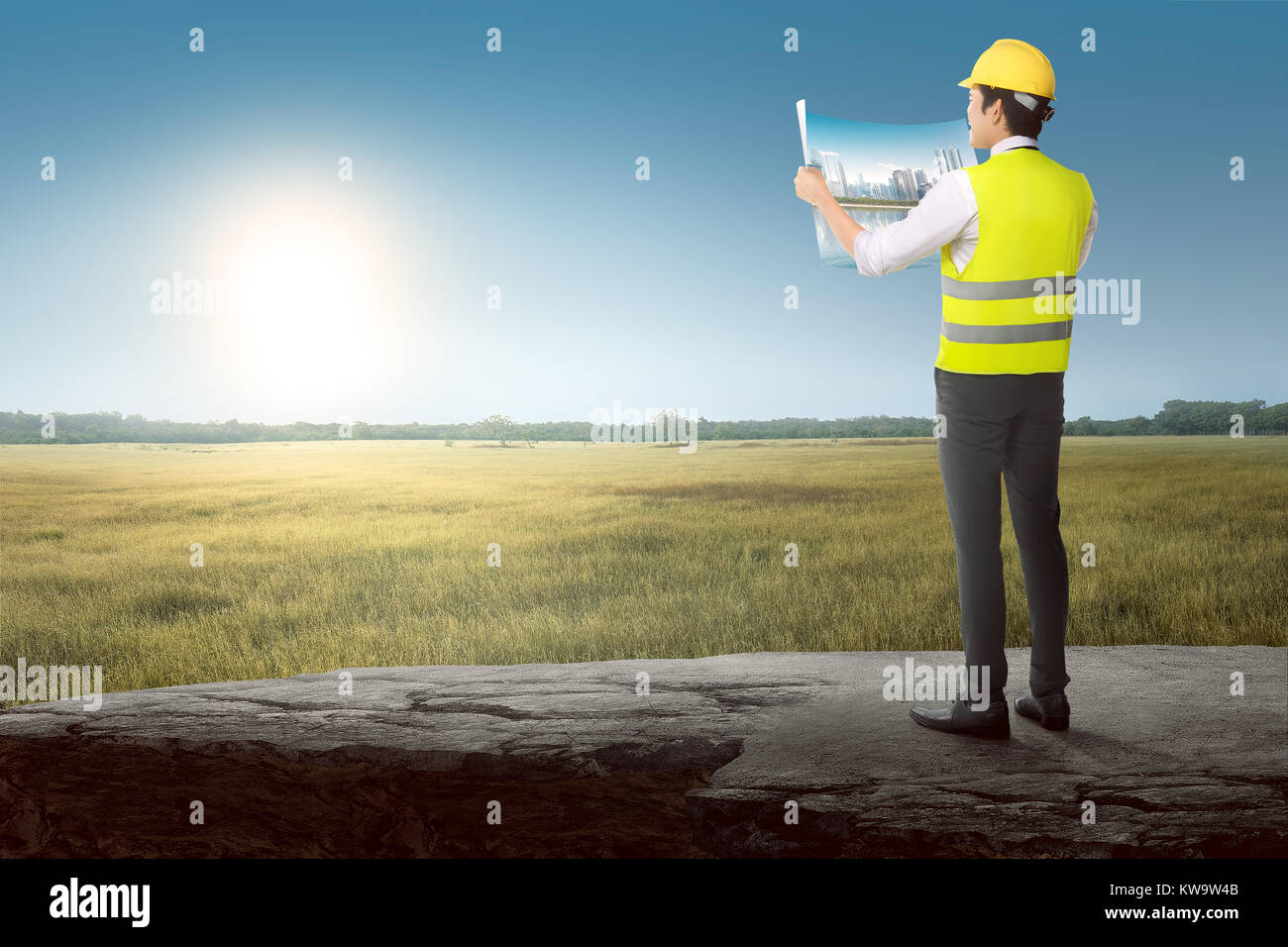 Back view of asian architect builder looking his layout plan on construction site Stock Photo