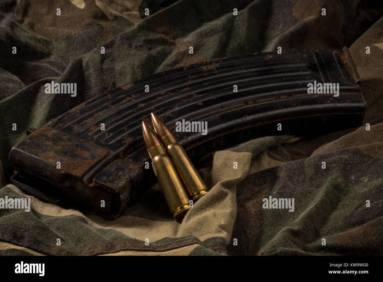 Rusty AK-47 magazine and bullets on camouflage textile background Stock Photo