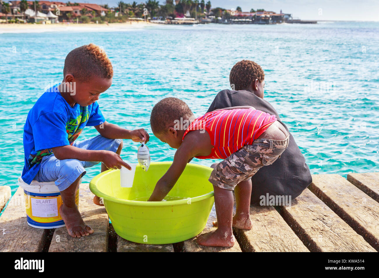 Three young boys fishing off the pier at Santa Maria, Sal Island, Salina, Cape Verde, Africa Stock Photo