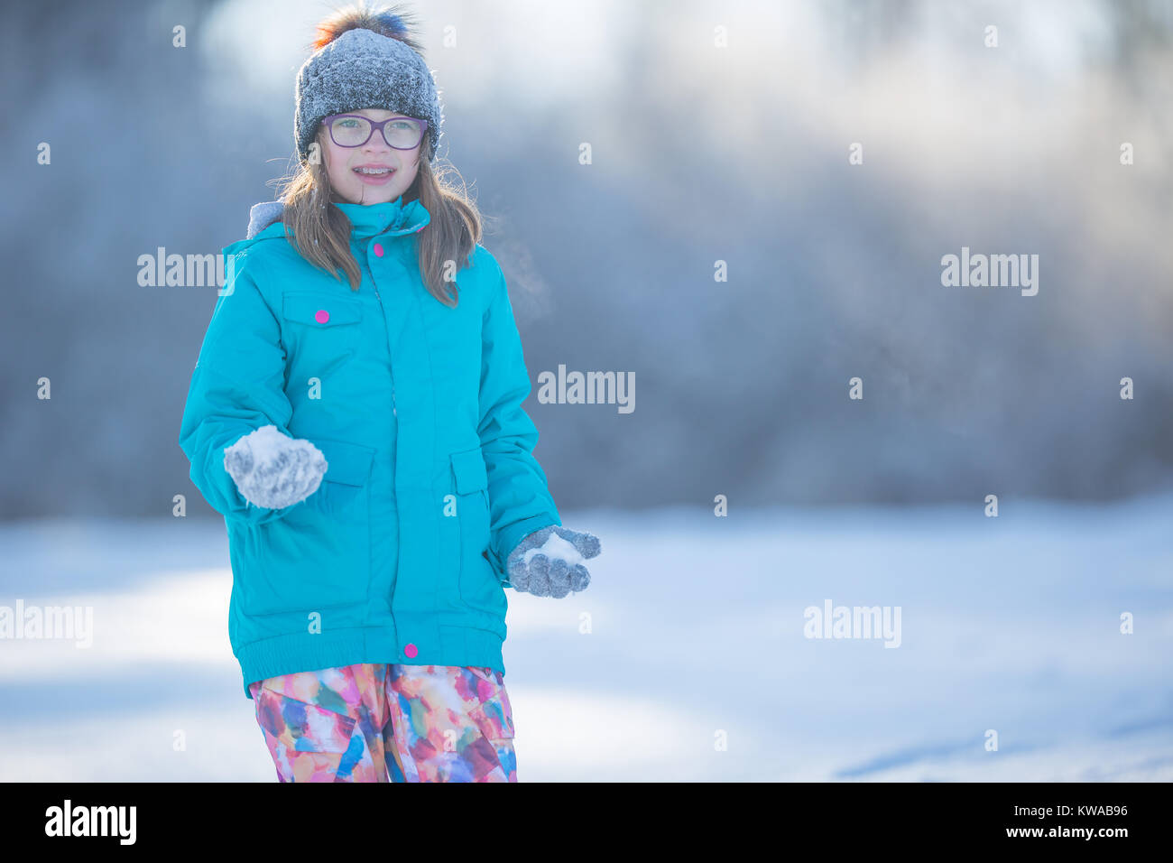 Happy young Pre-Teen girl in warm clothing  playing with snow. Stock Photo