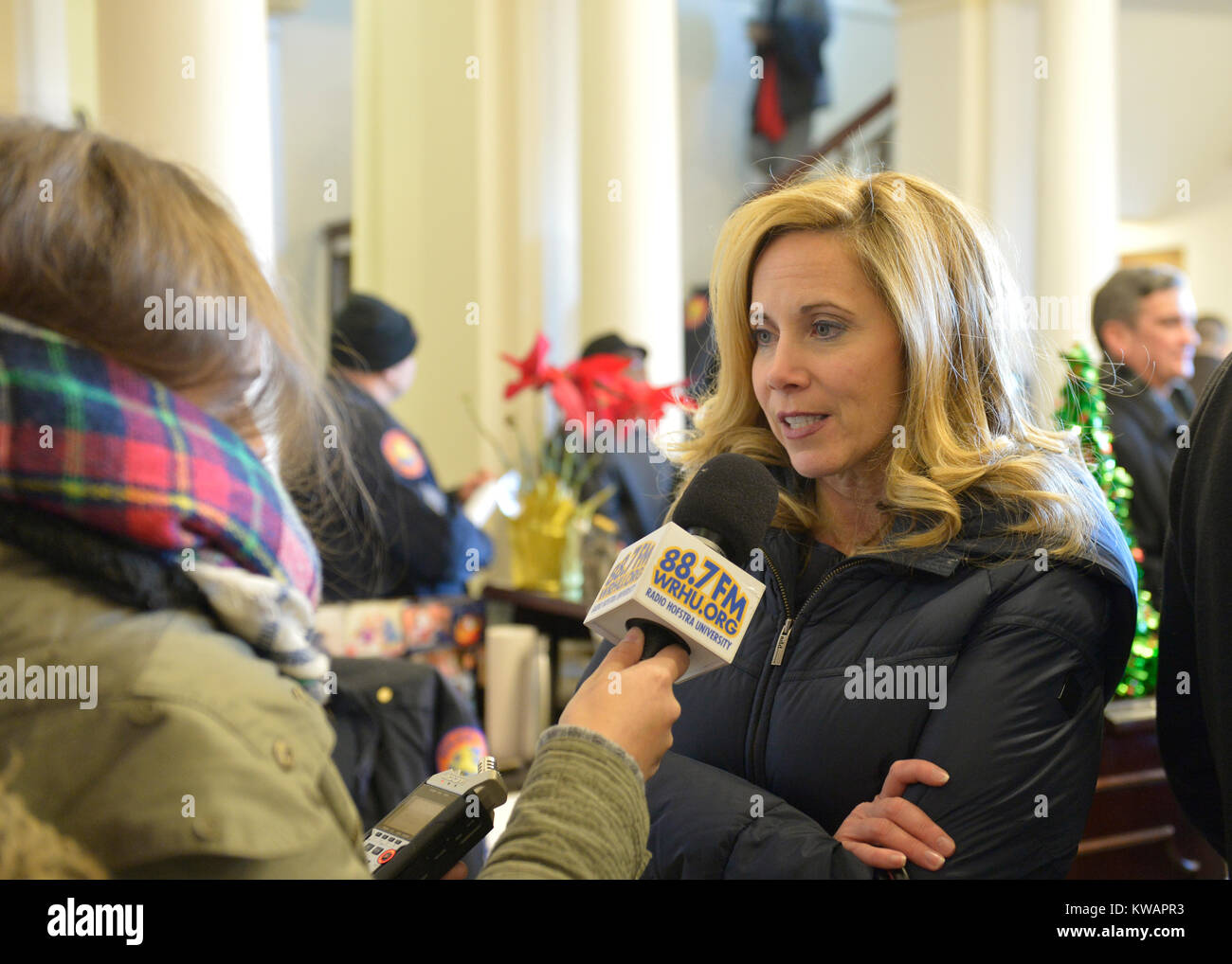 Mineola, New York, USA. January 1, 2018. Town of Hempstead Supervisor LAURA GILLEN, a Democrat, is interviewed by a reporter for Hofstra University's WRHU radio station, after historic swearing-In of Laura Curran as Nassau County Executive. They were in the Theodore Roosevelt Executive & Legislative Building, which the Curran swearing-in was held in front of the entrance outdoors. Gillen's swearing in was held that morning at Hofstra University. Stock Photo