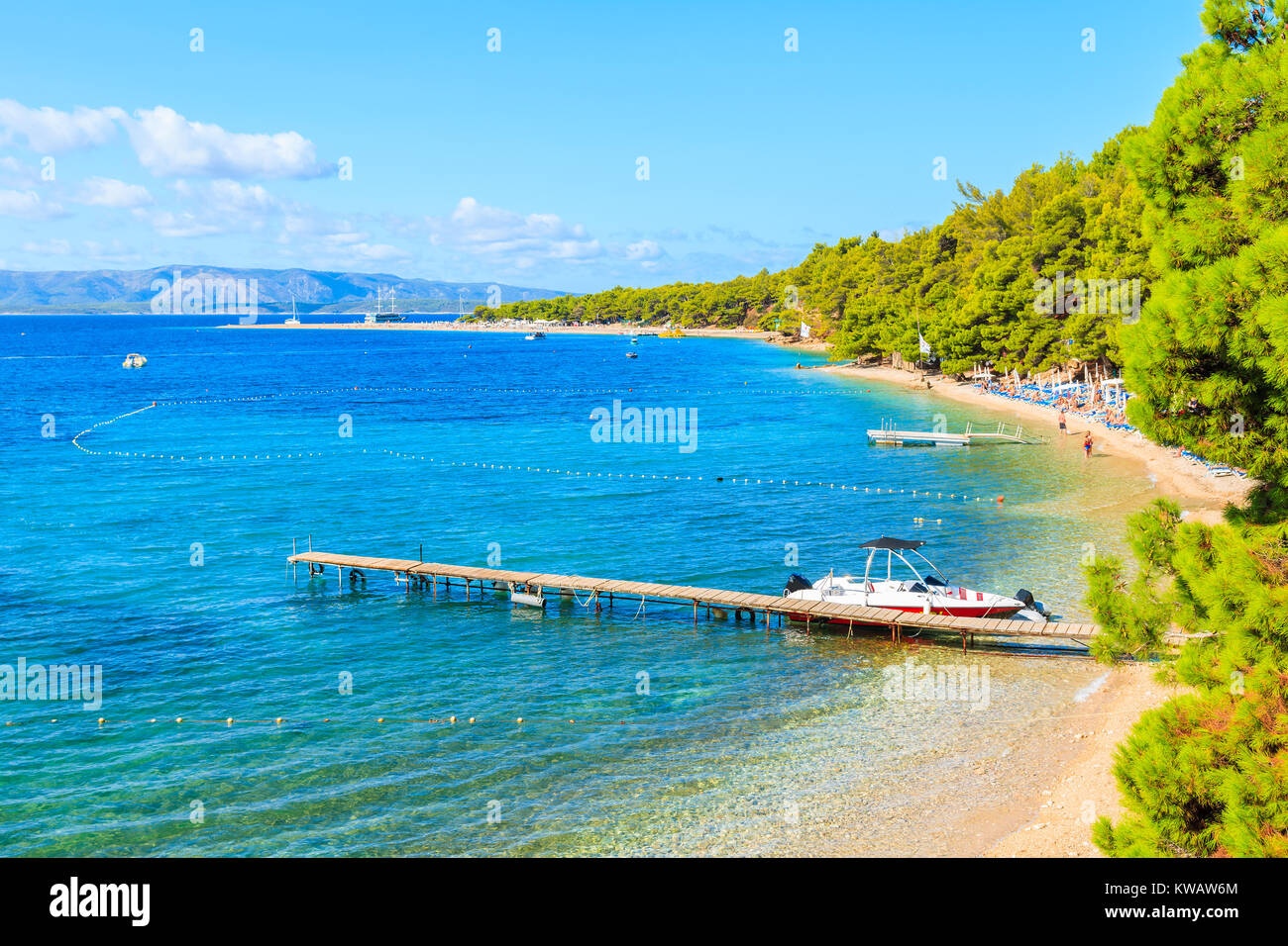 Tourist boat anchoring at beach pier near famous cape Zlatni Rat in Bol town, Brac island, Croatia Stock Photo