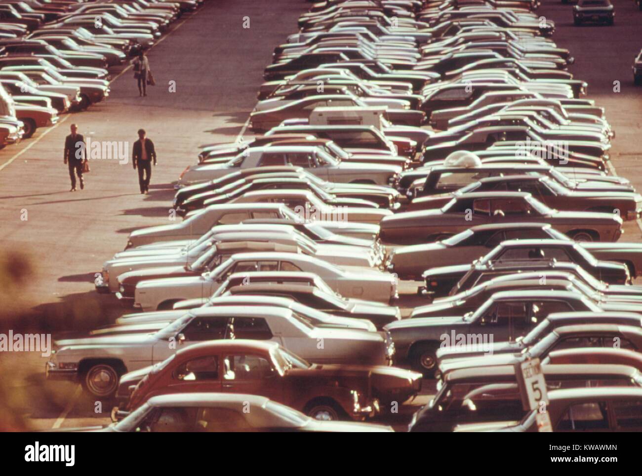 Men return to their cars at the end of the day in Monroe Street Parking Lot where hundreds of vehicles are parked in Chicago, Illinois, 1973. Image courtesy National Archives. Stock Photo