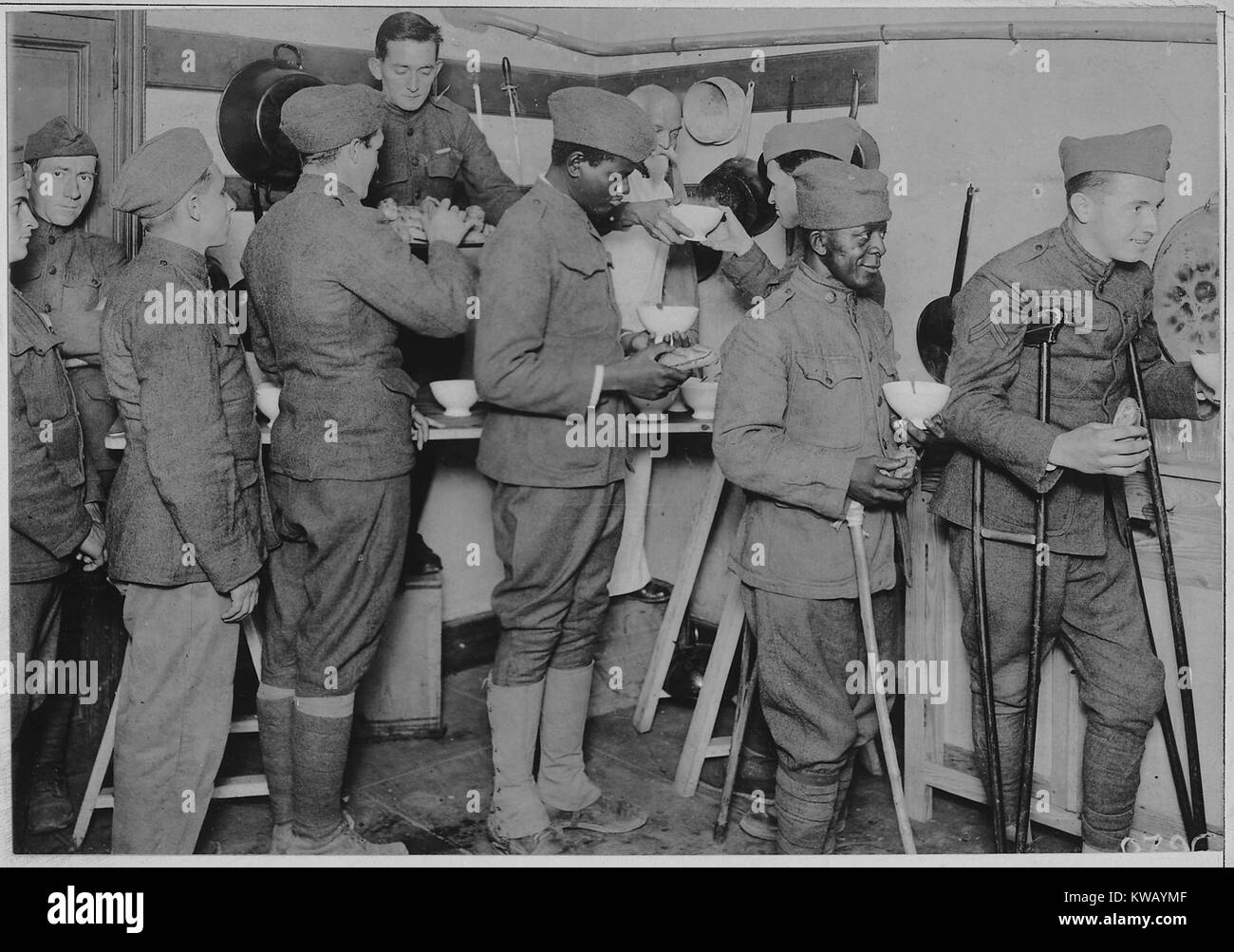 Happy American soldiers in uniform stand in line to receive bowls of chocolate and rolls at the American Red Cross canteen in Toulouse, France, 1917. Image courtesy National Archives. Stock Photo