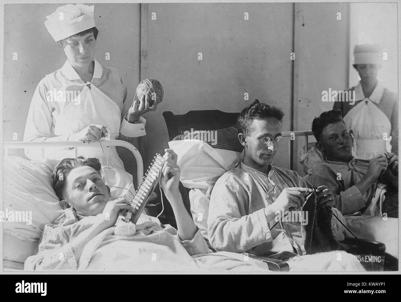 Three wounded soldiers knit from a hospital bed at Walter Reed Hospital, Washington, District of Columbia, 1917. Image courtesy National Archives. Stock Photo