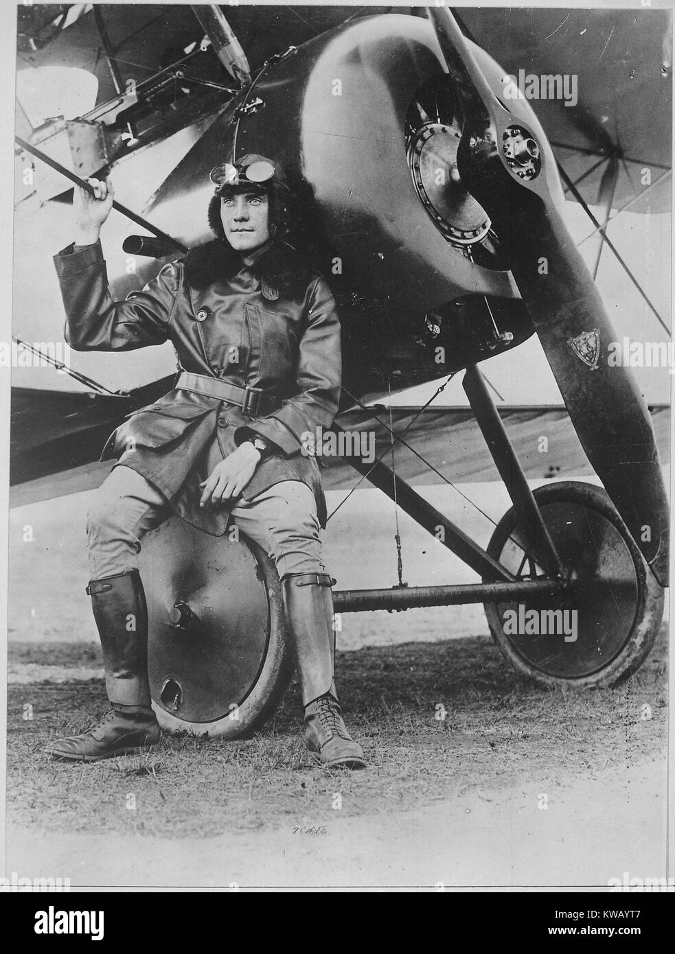 Renown US composer turned military aviator, Lieutenant Earl Carroll poses wearing boots, bomber, and aviator cap and glasses, leaning against his fast scout machine and gazing out of frame, International Film Service, 1918. Image courtesy National Archives. Stock Photo