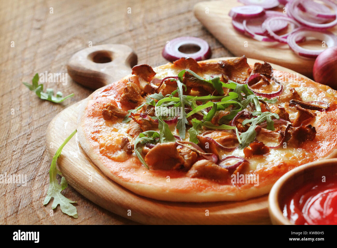 Pizza with mushrooms chanterelle, rucola on wooden table Stock Photo