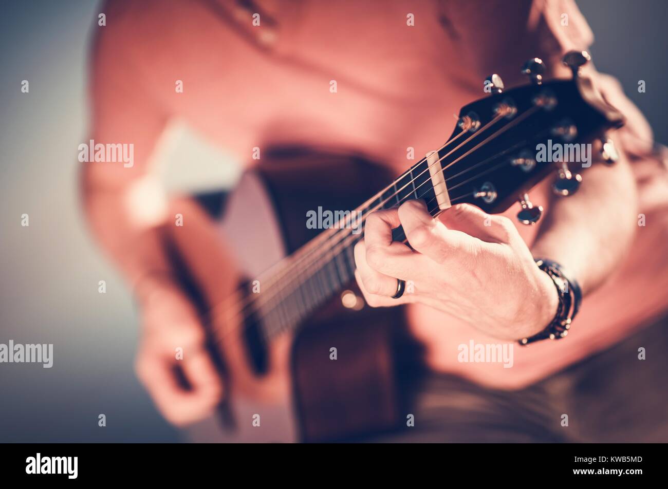 Caucasian Musician Playing Acoustic Guitar. Hand on Guitar Strings Closeup Photo. Music Performing. Stock Photo