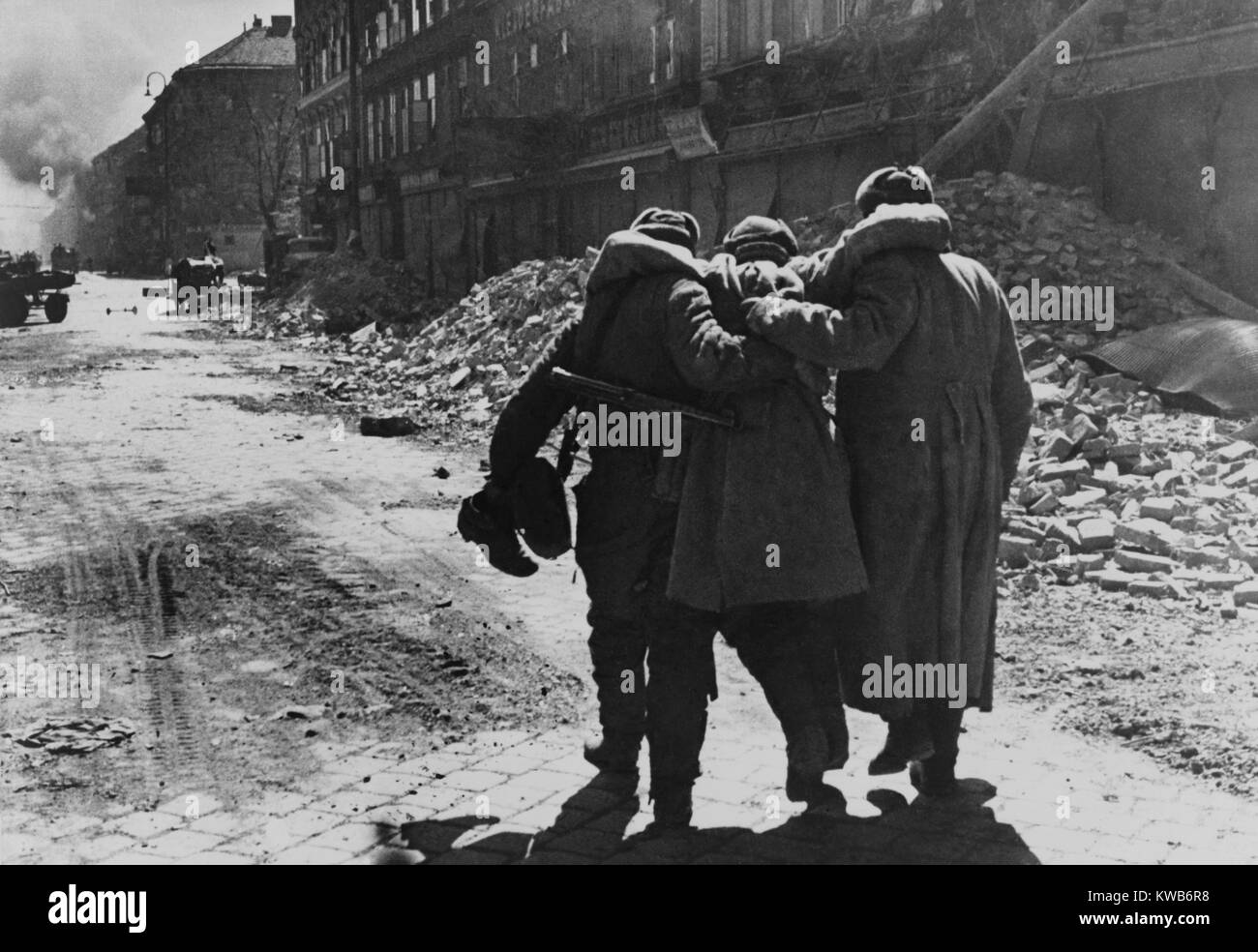 Wounded Soviet (Russian) soldier helped by two comrades in a street filled with rubble, Vienna. 1945 World War 2 photography by Evgenii Khaldei. (BSLOC 2014 8 29) Stock Photo