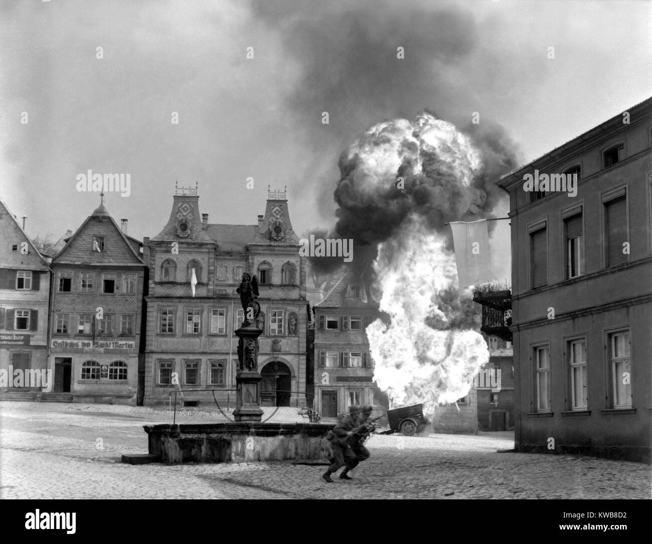 Two soldiers dash past a blazing German gasoline trailer in town square of Kronach, Germany. U.S. 101st Infantry, April 14, 1945. World War 2. (BSLOC 2014 8 75) Stock Photo