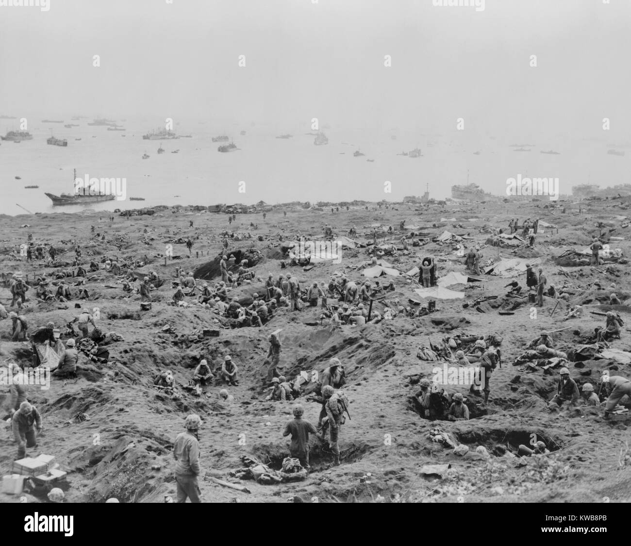 Marines in foxholes on the southeast edge of Motoyama Airfield #1, Iwo Jima. Landing craft are beached on right. February 23, 1945. World War 2. (BSLOC 2014 10 114) Stock Photo