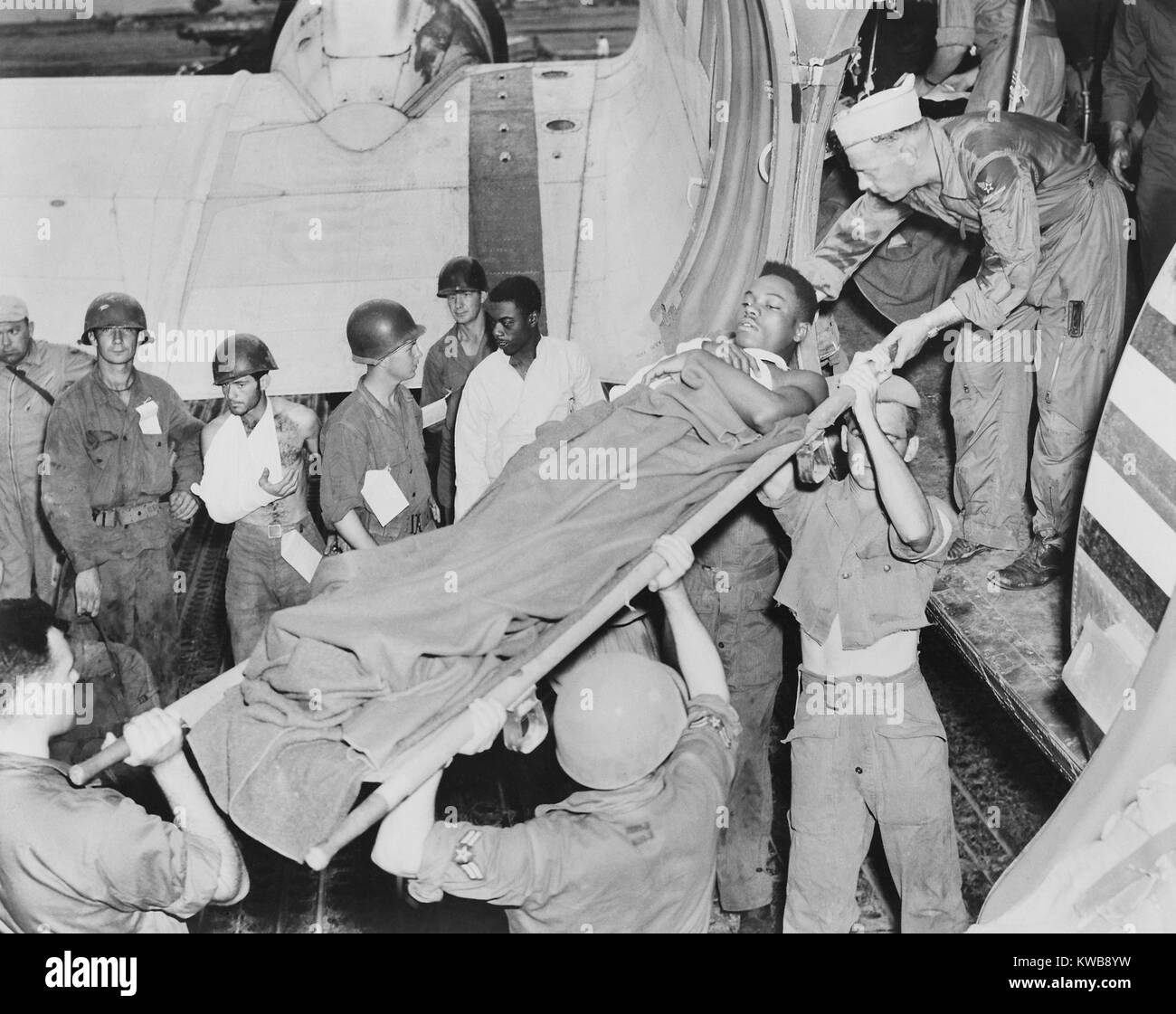 U.S. soldier is lifted from a Air Force C-47 in Japan from an airstrip near the battle front in Korea. Other wounded soldiers stand by the plane's wing. Air evacuation saved lives of many soldiers with wounds that killed in World War 2. Korean War, 1950-53. (BSLOC 2014 11 201) Stock Photo