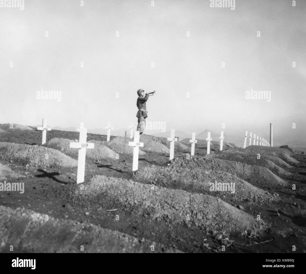 U.S. Marine plays 'Taps' over the graves of fallen Leathernecks during memorial services. The First Marine Division dead were brought from Chosin Reservoir to be buried in the cemetery at Hungnam, Korea. Dec. 13, 1950. Korean War, 1950-53. (BSLOC_2014_11_207) Stock Photo