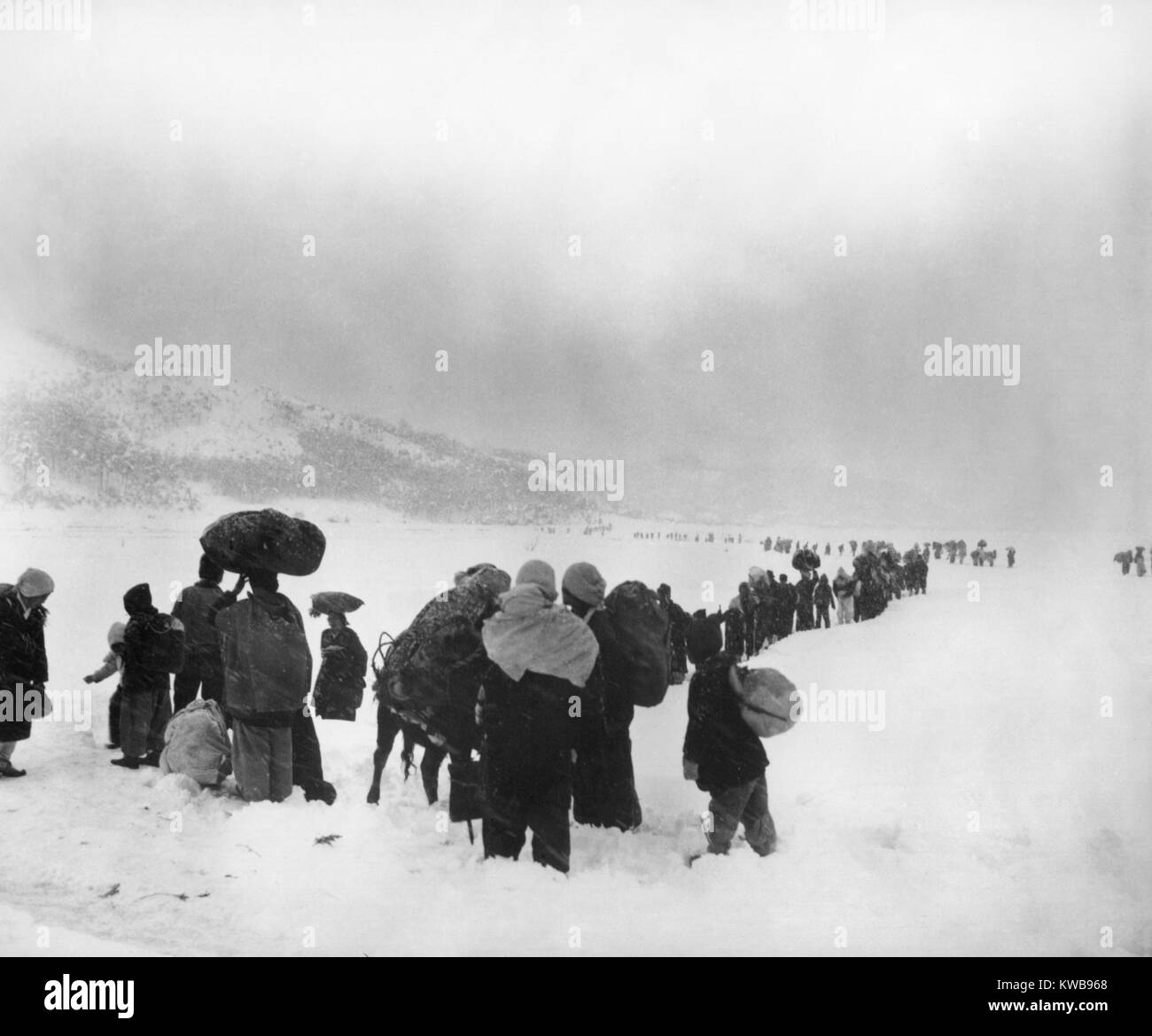 Korean refugees slog through snow outside of Kangnung (Gangneung), moving south with bundles of belongings. The South Korean Army was withdrawing south in the same area, with the North Korean/Chinese troops in pursuit. January 8, 1951. Korean War, 1950-53. (BSLOC_2014_11_245) Stock Photo