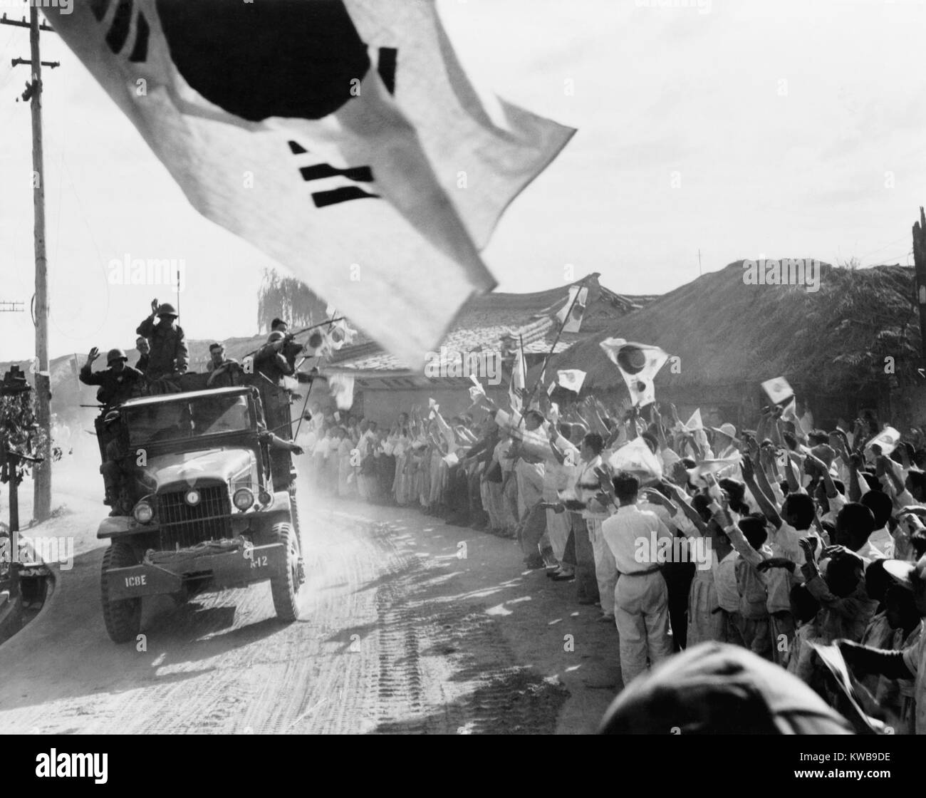 U.S. First Cavalry Division troops pass cheering Koreans north of Seoul on the way to the 38th parallel. A South Korean flag flies in foreground with smaller flags waved in the crowd. Ca. Oct. 9, 1950. Korean War, 1950-53. (BSLOC 2014 11 64) Stock Photo