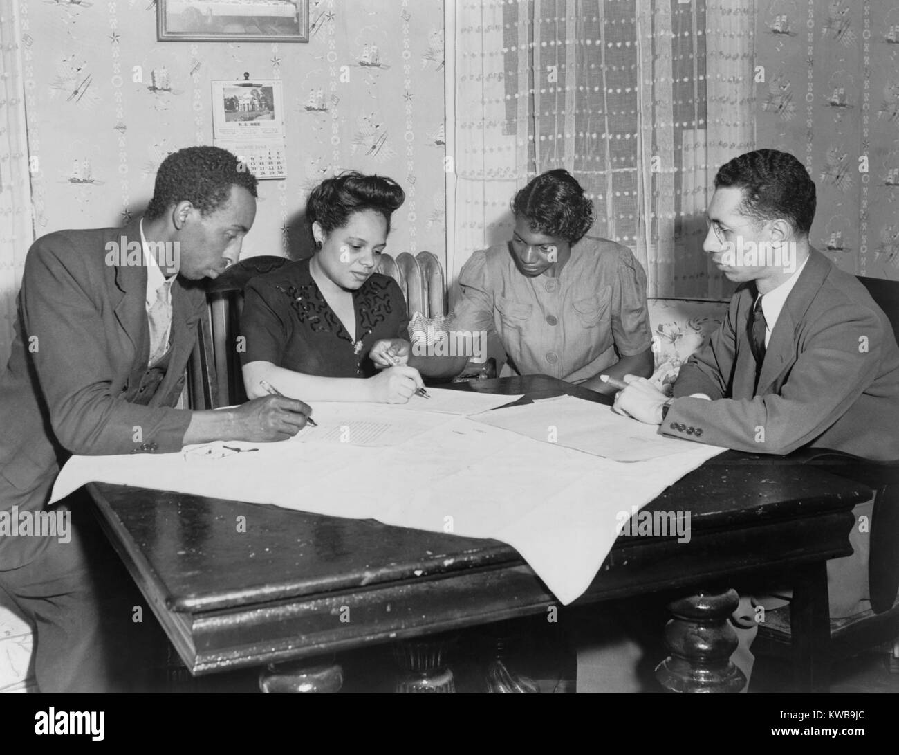 Polly Johnson (2nd from right) is assisted in signing an affidavit for the NAACP. It documented her involuntary servitude at the hands of Mr. and Mrs. Beale Broach, of King George Co., Virginia. For years, as a child and teenager, she was denied school, church, and friends as she performed forced labor on Beale farm and home. Ca. May 1946. (BSLOC 2014 13 113) Stock Photo