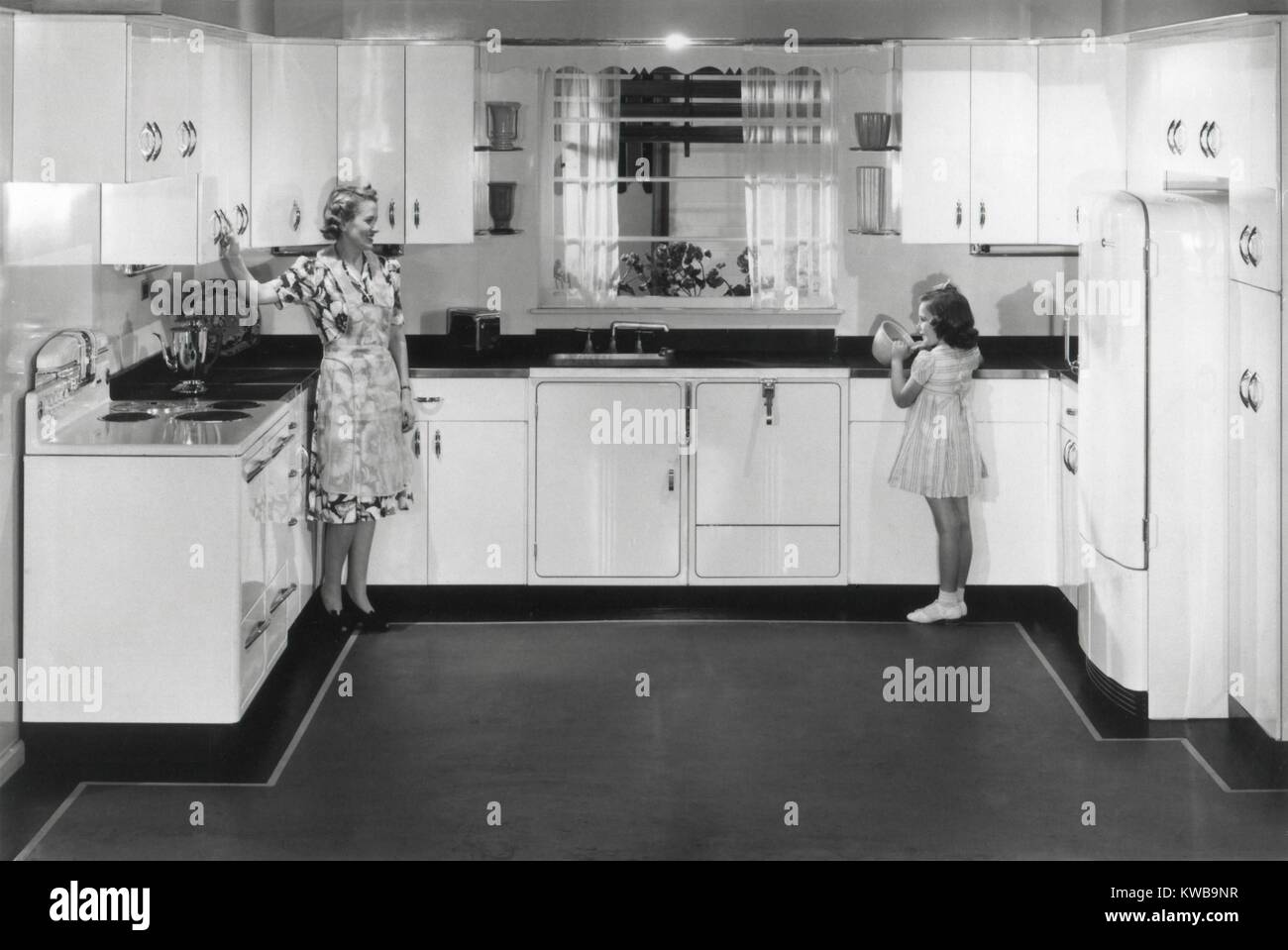 Modern electric kitchen with a stove and refrigerator. An electric dishwasher is to right of the sink. The all metal cabinets complete advanced design. Ca. 1950. (BSLOC 2014 13 152) Stock Photo