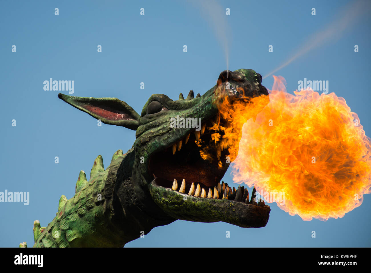 Green dragon & orange fireball on blue sky background Stock Photo