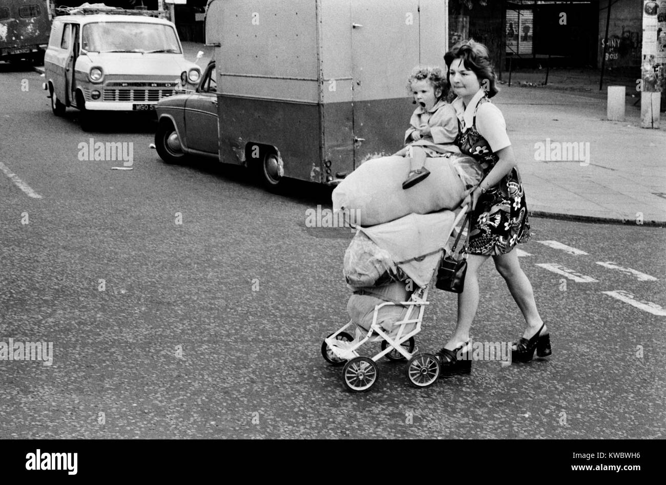 1970s poverty poor family London. Siblings teen girl pushing pram stacked with food shopping and young sister they are going home. The north end of the Portobello Road. West London Britain 70s UK HOMER SYKES Stock Photo