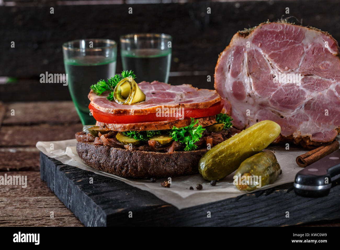 Homemade rye sandwich with smoked ham, tomato, onion jam, pickles and ...