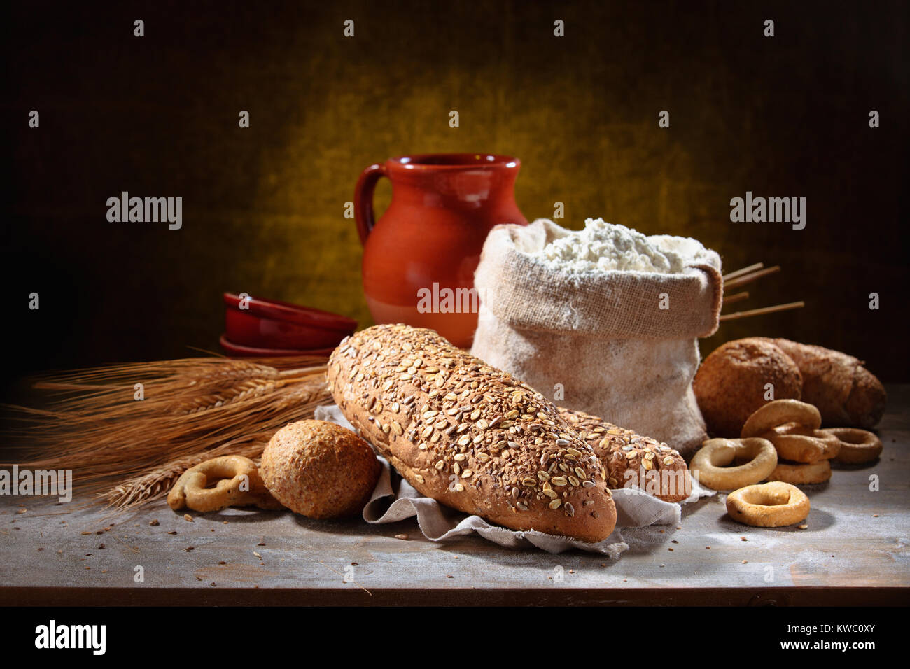 Rustic bread and wheat on rustic wood table. Dark moody background with ...