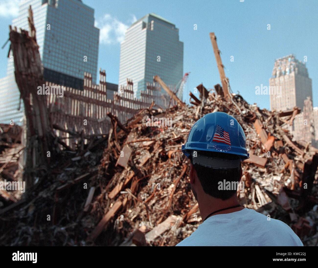 Worker at the 'pile' of rubble from the collapse of WTC 2, the South Tower on Oct. 3, 2001. The ruins of the Twin Towers formed 15 meters high piles. In the background are damaged but repairable buildings: L-R: World Financial Center 2 and 3, and the New York Telephone Building (Verizon Building). (BSLOC 2015 2 111) Stock Photo