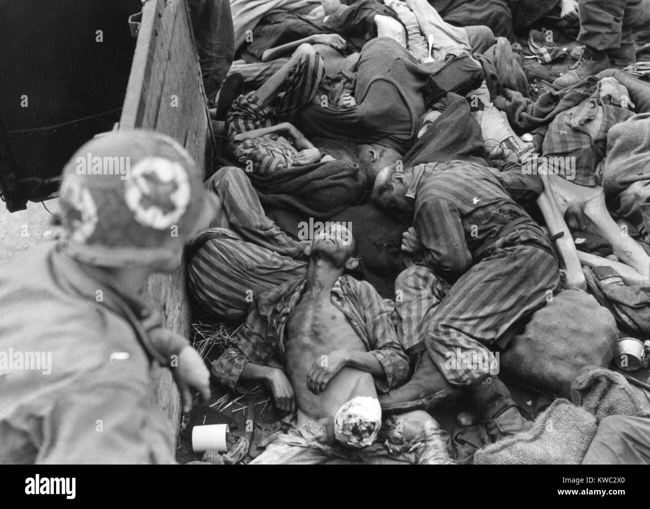 Seventh US Army Medical Corpsman looks into train car filled with slain or starved prisoners. As Nazi-Germany collapsed in March 1945, SS Guards shipped these bodies to Dachau for cremation. Many Nazi SS Guards deserted the camp as US army approached in April 1945. World War 2 (BSLOC 2015 13 13) Stock Photo