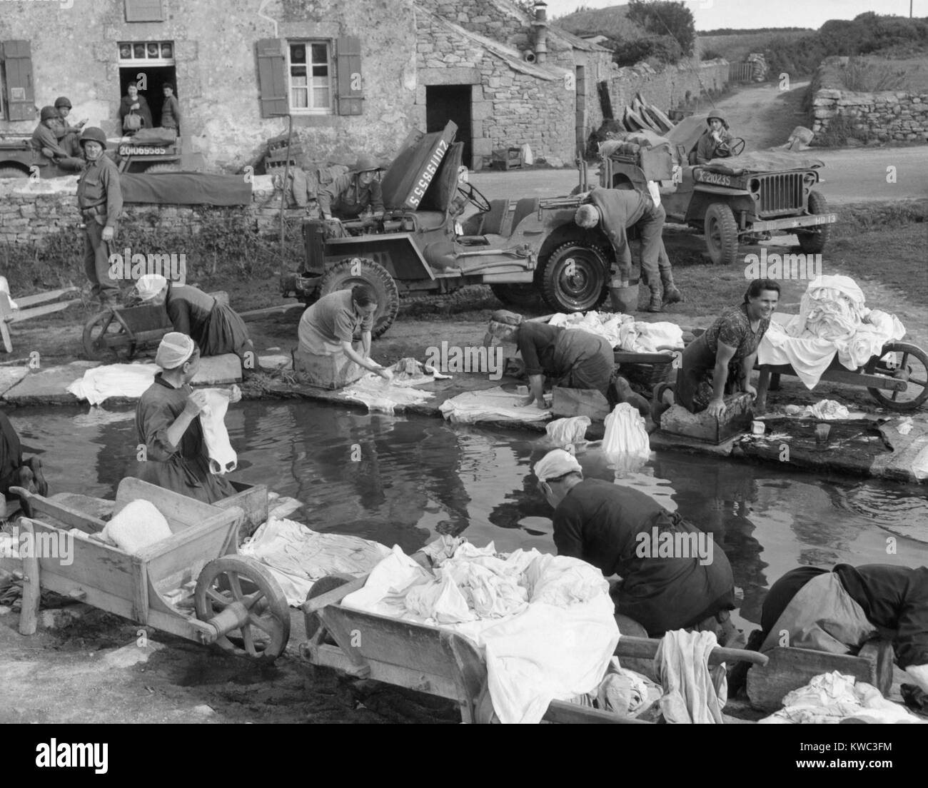 French village women doing their share their laundry facility with GI's washing their Jeep. Sept. 20, 1944, World War 2 (BSLOC 2015 13 84) Stock Photo