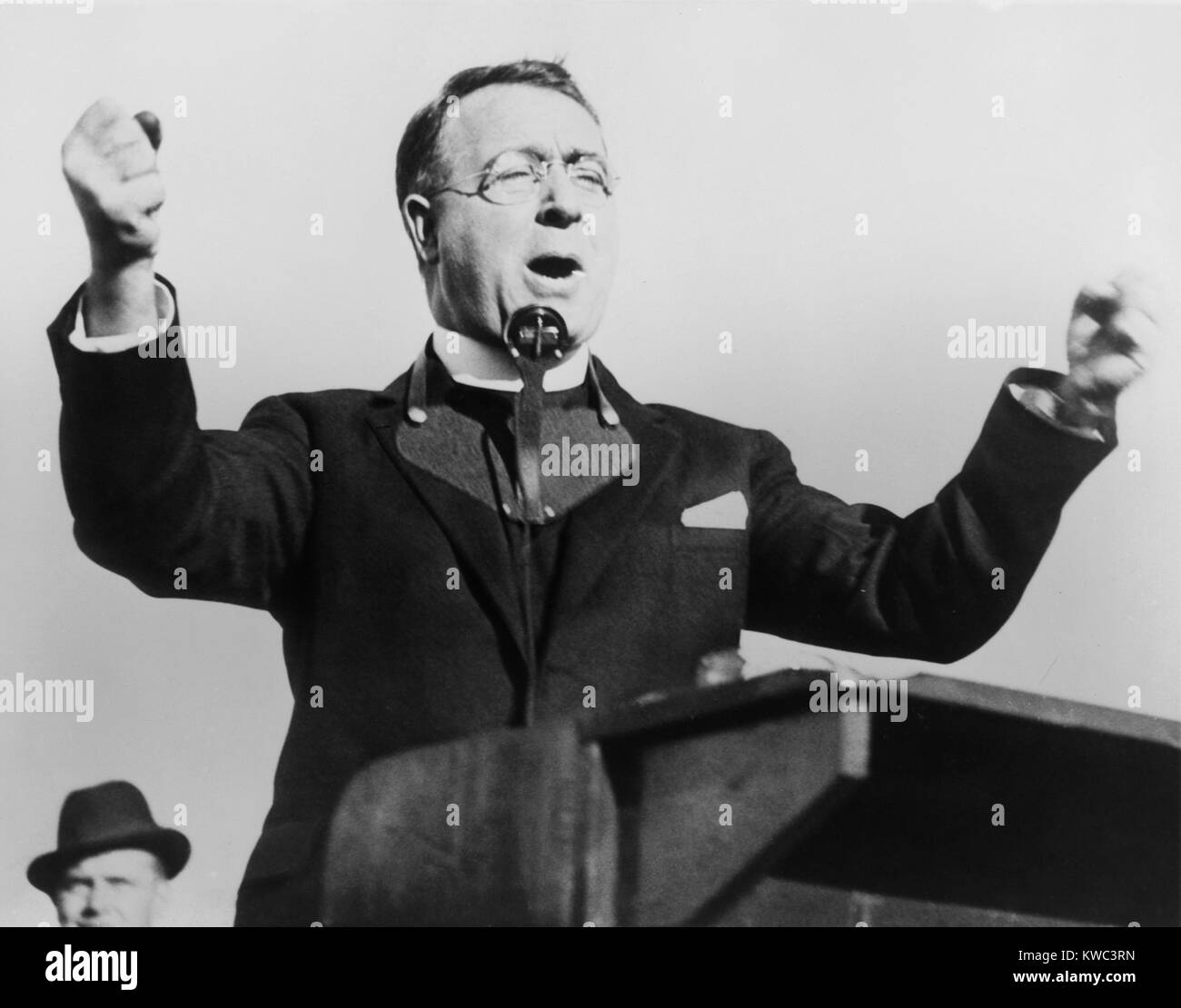 Charles Coughlin, with fists raised, attacks the New Deal in Boston, 1936. Wearing a microphone around his neck, he spoke at the National League baseball field, Boston. (BSLOC 2015 14 18) Stock Photo