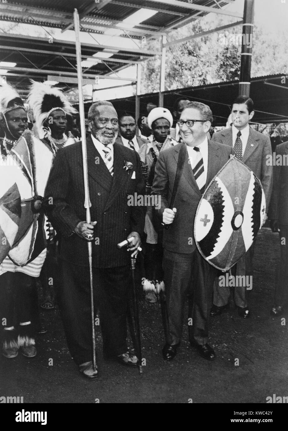 Henry Kissinger, standing with President Jomo Kenyatta, in Nairobi, Kenya, 1976. Kissinger holds a shield and sword, while Kenyatta has a pike. April 27, 1976. (BSLOC 2015 14 50) Stock Photo