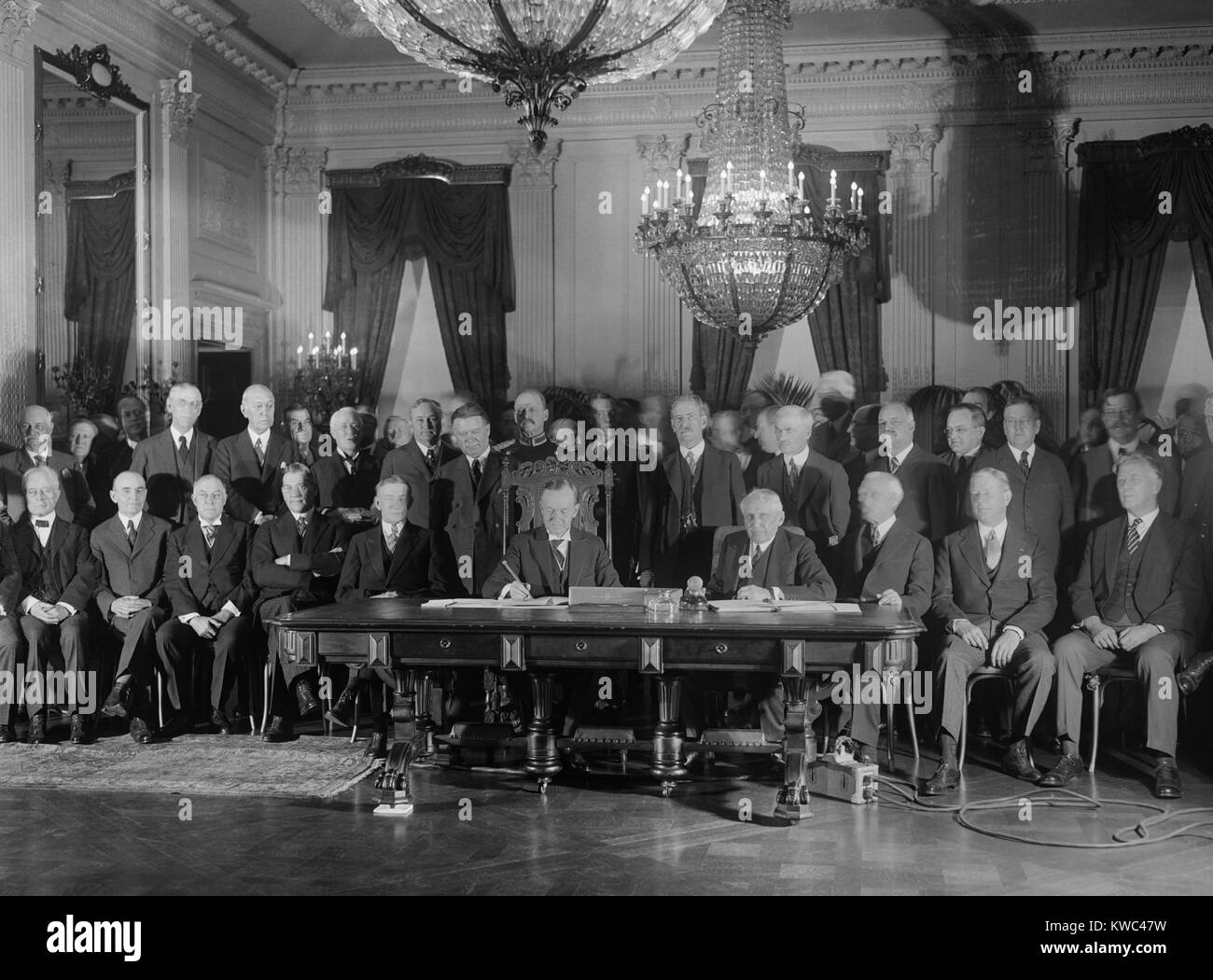 President Coolidge signs Kellogg Treaty in the East Room of the White House on Jan. 17, 1929. Kellogg-Briand Pact was an multi-national agreement to outlaw war. At table, L-R: Vice President Dawes, Pres. Coolidge, Sec. of State Frank Kellogg. Standing men include: William Borah; Sen. Claude Swanson; Sen. Thomas Walsh; VP-elect Charles Curtis; and Sen. D.O. Hastings (BSLOC 2015 15 122) Stock Photo