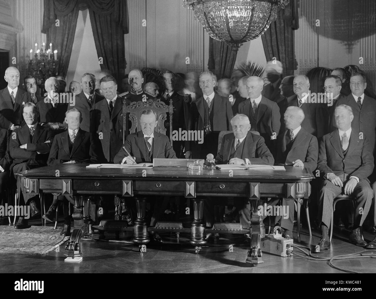 President Coolidge signs Kellogg Treaty in the East Room of the White House on Jan. 17, 1929. Kellogg-Briand Pact was an multi-national agreement to outlaw war. At table, L-R: Vice President Dawes, Pres. Coolidge, Sec. of State Frank Kellogg. (BSLOC 2015 15 123) Stock Photo