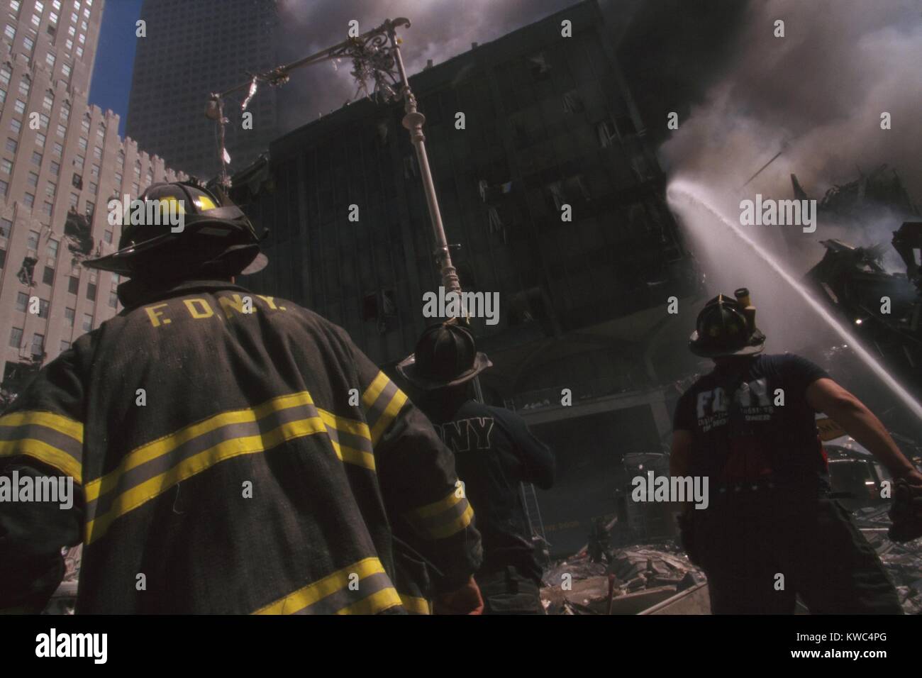 Fire fighter at World Trade Center site following September 11th terrorist attack. The stream water is to the still standing WTC 6. At left is the New York Telephone Company Building, damaged but repairable. (BSLOC 2015 2 56) Stock Photo